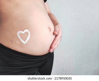 Stretch Marks On The Skin During Pregnancy. Skin Care During Pregnancy Concept. Heart Shape Created From Cream. 