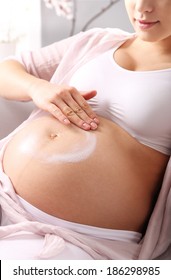 Stretch marks in pregnancy . A pregnant woman rubs lotion on big pregnancy belly  - Shutterstock ID 186298985