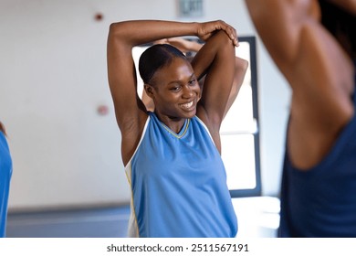 Stretching arms, female basketball player smiling during practice session in gym. Sports, training, athlete, workout, fitness, teamwork - Powered by Shutterstock