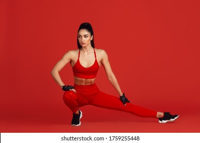 Stretching. Beautiful Young Female Athlete Practicing In Studio, Monochrome Red Portrait. Sportive Fit Brunette Model Training. Body Building, Healthy Lifestyle, Beauty And Action Concept. Copyspace.