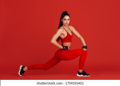 Stretching. Beautiful Young Female Athlete Practicing In Studio, Monochrome Red Portrait. Sportive Fit Brunette Model Training. Body Building, Healthy Lifestyle, Beauty And Action Concept. Copyspace.