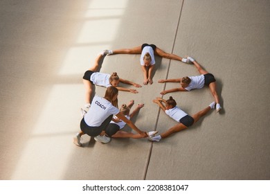 Stretching, Flexibility Exercises. Aerial View. Female Sports Coach Training Gymnastics Athletes At Sports Gym, Indoors. Concept Of Achievements, Studying, Goals. Coaching, Training, Psychology