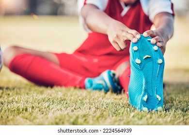 Stretching, foot and soccer player on field for sports training, exercise and legs muscle wellness health zoom. Football athlete with shoes or sneakers gear for warmup workout or game on grass pitch