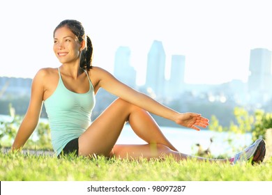 Stretching woman in outdoor exercise smiling happy doing yoga stretches after running. Beautiful happy smiling sport fitness model outside on summer / spring day. - Powered by Shutterstock