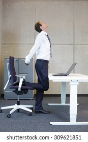 Stretching - Young Businessman In Standing Position Taking Short Break For Exercise In Office Work