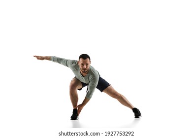 Stretching. Young caucasian male model in action, motion isolated on white background with copyspace. Concept of sport, movement, energy and dynamic, healthy lifestyle. Training, practicing. Authentic - Powered by Shutterstock