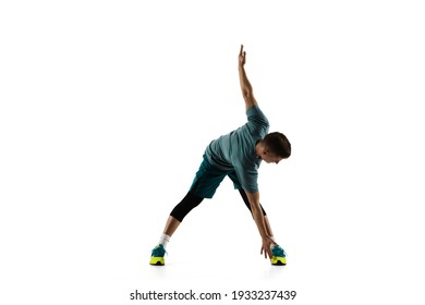 Stretching. Young caucasian male model in action, motion isolated on white background with copyspace. Concept of sport, movement, energy and dynamic, healthy lifestyle. Training, practicing. Authentic