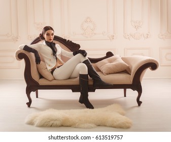 Strict, beautiful girl in elegant rider suit poses on camera. Restrained interior, vintage sofa. Unusual hairstyle and makeup - Shutterstock ID 613519757