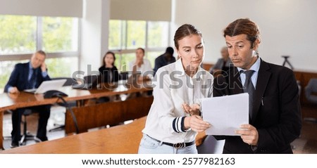 Strict director checking documents from a female manager in a meeting room