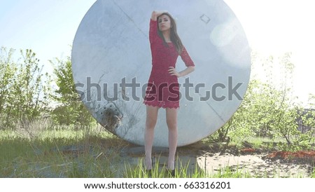 Strict girl. A serious girl stands near a barrel of petrol oil. An old barrel oil