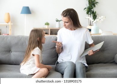 Strict Mother Scolding Little Daughter For Long Laptop Use, Angry Woman With Preschool Girl Sitting On Couch In Living Room, Holding Computer In Hands, Parent Reprimanding, Lecturing Child