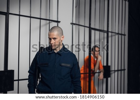A strict prison guard in uniform guards cells with prisoners in a maximum security prison
