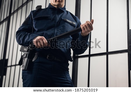 A strict prison guard in uniform guards cells with prisoners in a maximum security prison