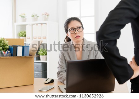 Strict supervisor standing in the front of the computer and oversight the employee doing her work.