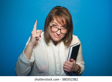 strict teacher with glasses and book in hand on blue background, studio