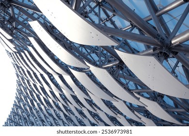 A striking architectural structure showcases a curved facade made of metallic elements and white panels, illuminated by sunlight. The design emphasizes modern construction techniques. - Powered by Shutterstock