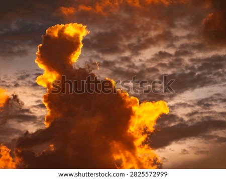 Striking cloudscape at sunset in summer, with dark, anthropomorphic figure like a mythical giant on fire and in motion. Motifs of pareidolia, fight-or-flight response, legend.