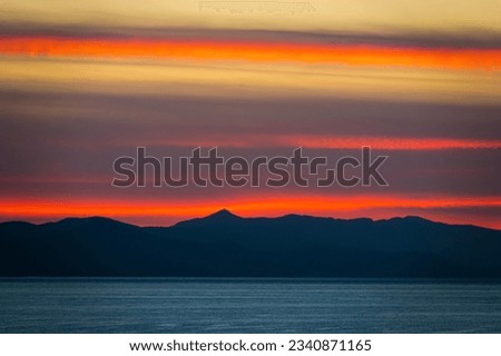 Striking colors of sunset clouds over a mountain silhouette on Croatian coast. Breathtaking evening sky by the beautiful Adriatic Sea. Picturesque moments from summer holidays on the island of Hvar.