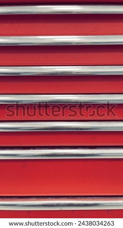 Striking Contrast: Red Metal Shutters with Silver Bars. A Bold Red Texture Adds Vibrancy to the Industrial Design. Close up