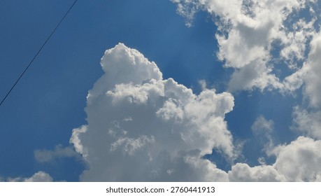 A striking image capturing the immense scale and texture of a large cumulonimbus cloud against a clear, vibrant blue sky, showcasing nature's atmospheric artistry.