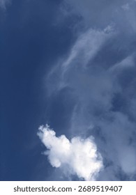 A striking image capturing a singular, fluffy white cumulus cloud adrift in a serene, deep blue sky. The contrasting colors evoke feelings of tranquility, freedom, and the sheer beauty of nature.