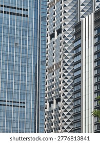 A striking image showcasing the contrast between a sleek glass skyscraper and a textured, geometric facade, highlighting modern architectural design.
