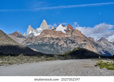 the striking Mount Fitz Roy in Patagonia, Argentina, with its jagged granite peaks and snow-capped summits set against a brilliant blue sky and rugged terrain. - Powered by Shutterstock