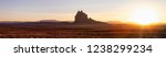 Striking panoramic landscape view of a dry desert with a mountain peak in the background during a vibrant sunset. Taken at Shiprock, New Mexico, United States.