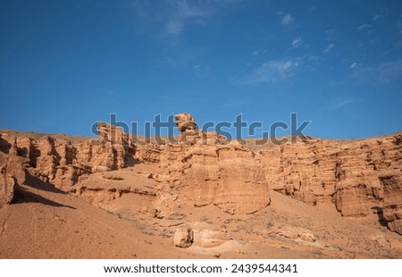 a striking range of massive red sandstone formations under a vast blue sky, hinting at a tranquil desert setting in the warm, gentle light of a late summer afternoon
