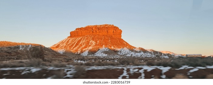 A striking red mountain looms in contrast against the snow-covered desert, a beacon of warmth and color in the stark, monochromatic landscape. - Powered by Shutterstock