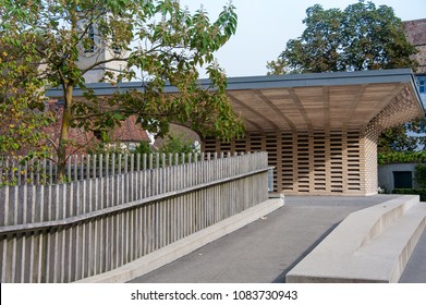 Striking roofline of the Stadtgarten Pavillon, part of the city gardens and municipal car park in Zug, Switzerland. Modern structure contrasts with old town buildings and blue sky - Shutterstock ID 1083730943