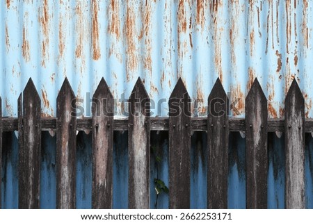 A striking visual contrast between weathered wooden pickets and a distressed blue corrugated metal background, perfect for adding rustic or industrial texture to projects.