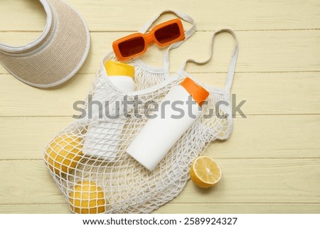 String bag with beach accessories and lemons on wooden background