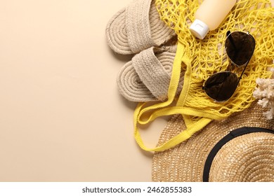 String bag and different beach accessories on beige background, top view. Space for text