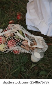a string bag with fresh red apples lies on the grass. Autumn harvesting.