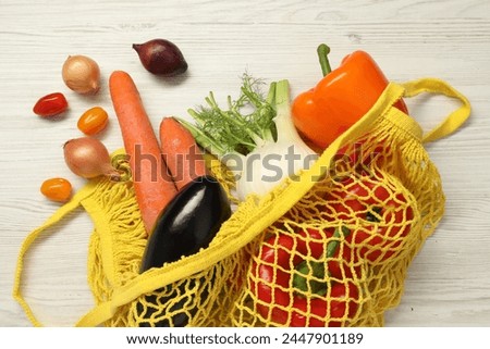 String bag with fresh vegetables on white wooden background, flat lay