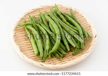 String beans on bamboo sieve on white background