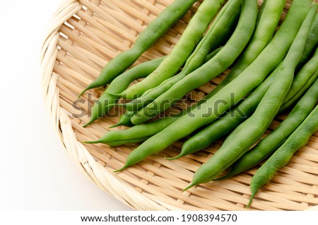 String beans on bamboo sieve on white background