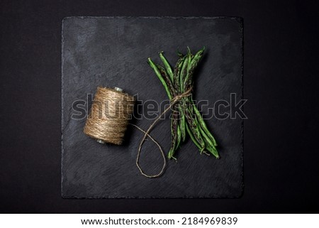String beans on a black background. A bunch of raw green beans tied with a rope. healthy vegetable