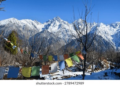 String of colorful Buddhist prayer flags hanging against a backdrop of snow-capped mountains fluttering in the breeze represents spiritual, peace, compassion, harmony between faith and nature