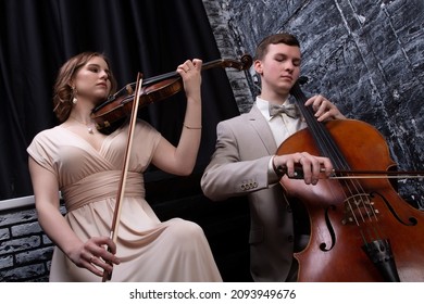 String Duet Of Young Woman And Man Play Music On The Cello And Violin