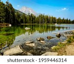String Lake in Grand Teton National Park on a clear day with beautiful reflections in the still water and the mountains in the background.