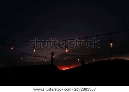 String light bulbs illuminating the dark sky at sunset