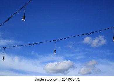 String of light bulbs under a blue sky. 
