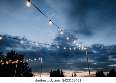 string lights with bare lightbulbs at twilight in Maine - Powered by Shutterstock