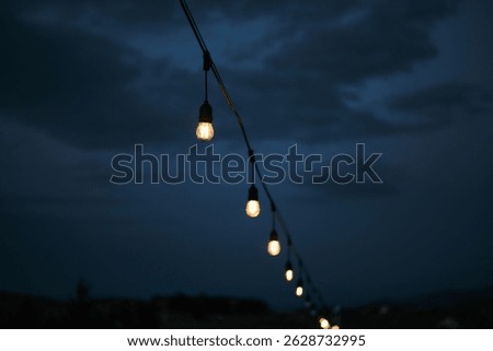 String lights glowing softly against a dramatic twilight sky. Perfect for projects needing a touch of moody, atmospheric lighting. Ideal for backgrounds, blogs, or websites.