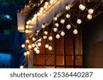 A string of lights hanging from a building. The lights are lit up and the mood is warm and inviting