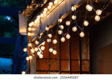 A string of lights hanging from a building. The lights are lit up and the mood is warm and inviting - Powered by Shutterstock