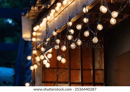 A string of lights hanging from a building. The lights are lit up and the mood is warm and inviting
