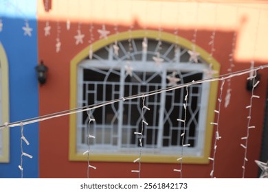 A string of lights hangs from the window of a building. The lights are arranged in a star pattern